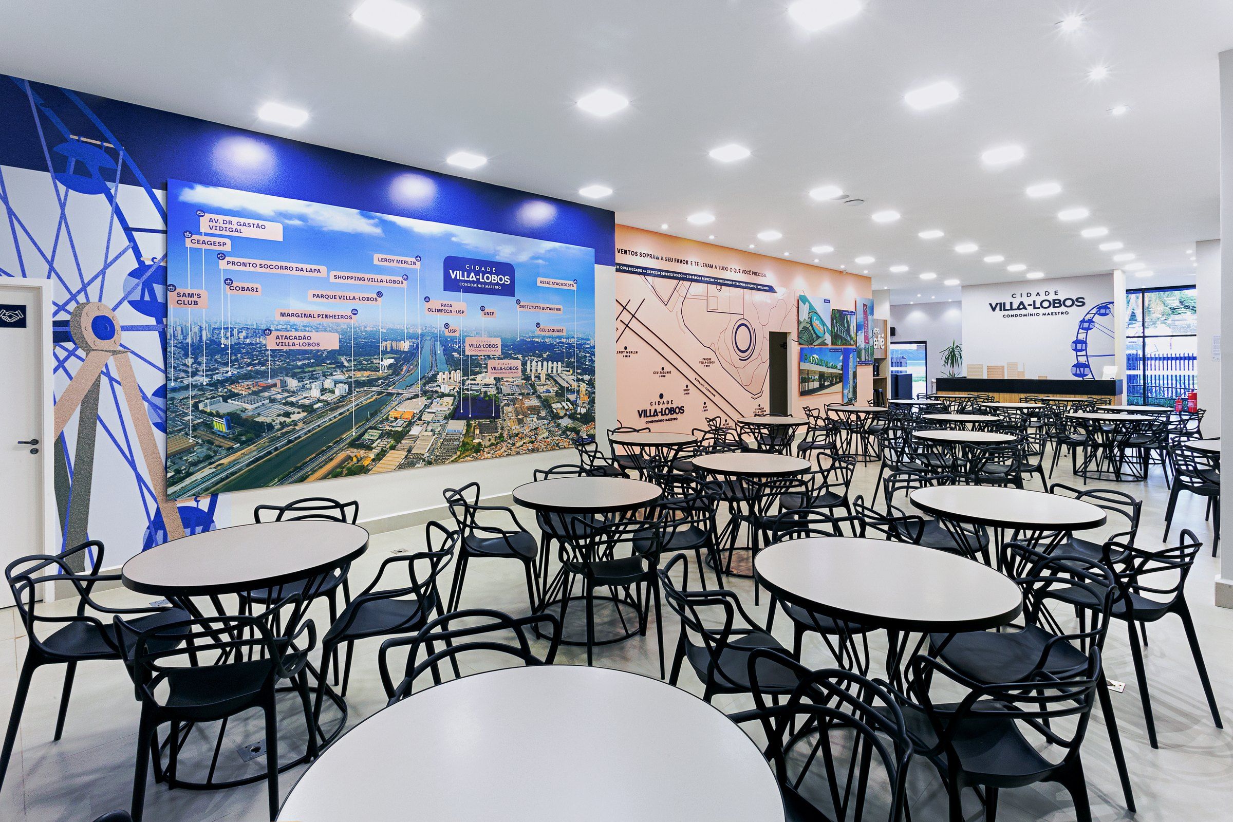 Salão do estande Cidade Villa-Lobos com mapa adesivado na parede e mesas
