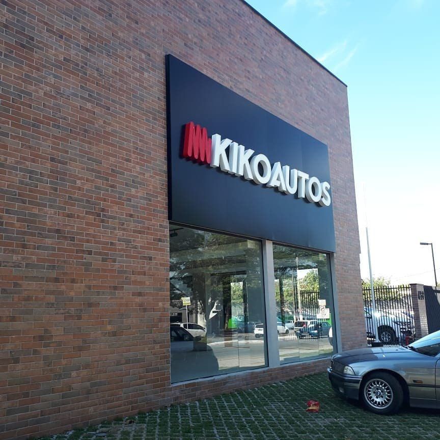 Fachada da Kiko Autos em tijolo com painel em ACM preto e letras caixa